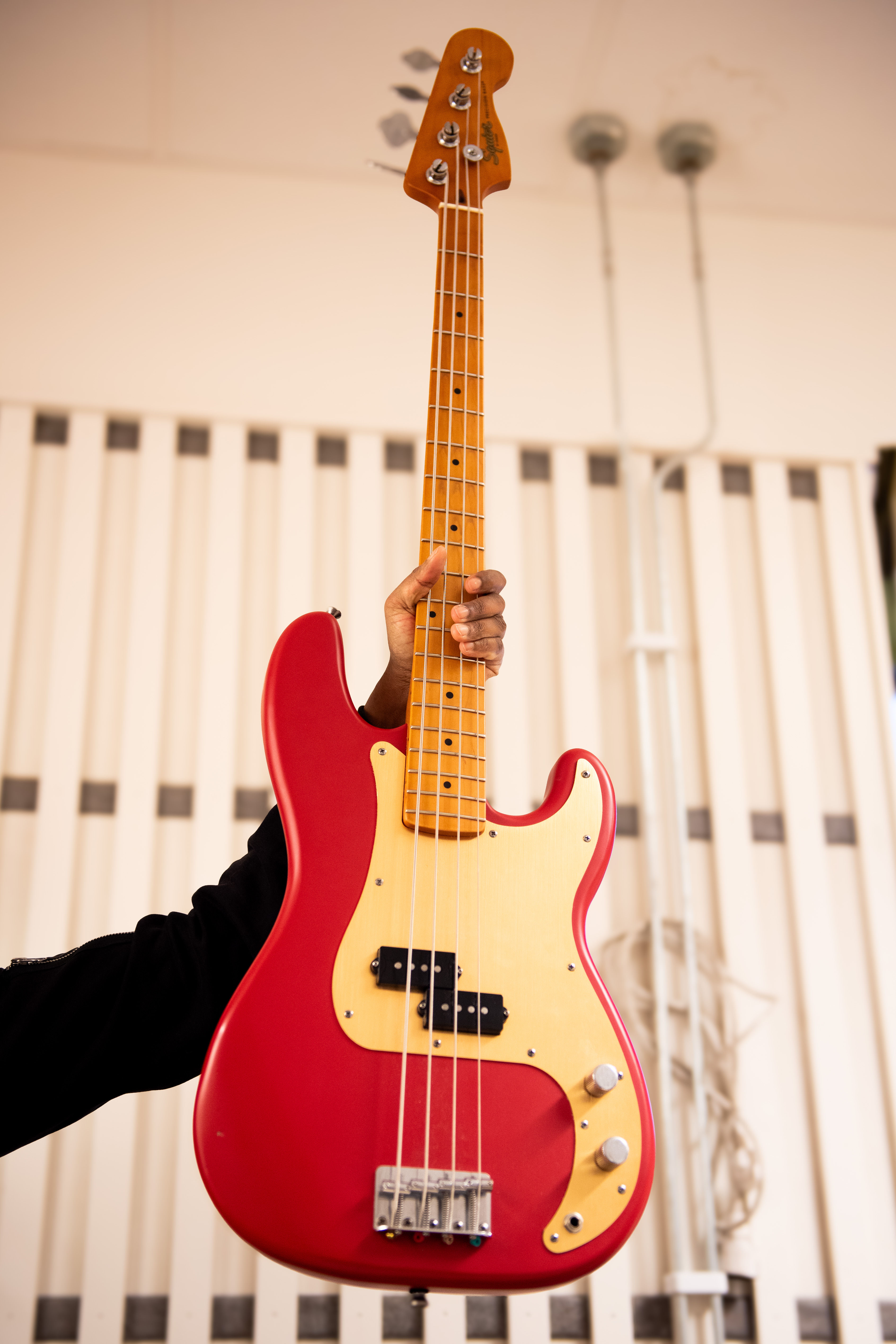 Bild på en röd elbas mot en vit akustikpanel