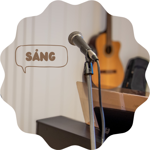 Bild på en sångmic och gitarr i bakgrunden