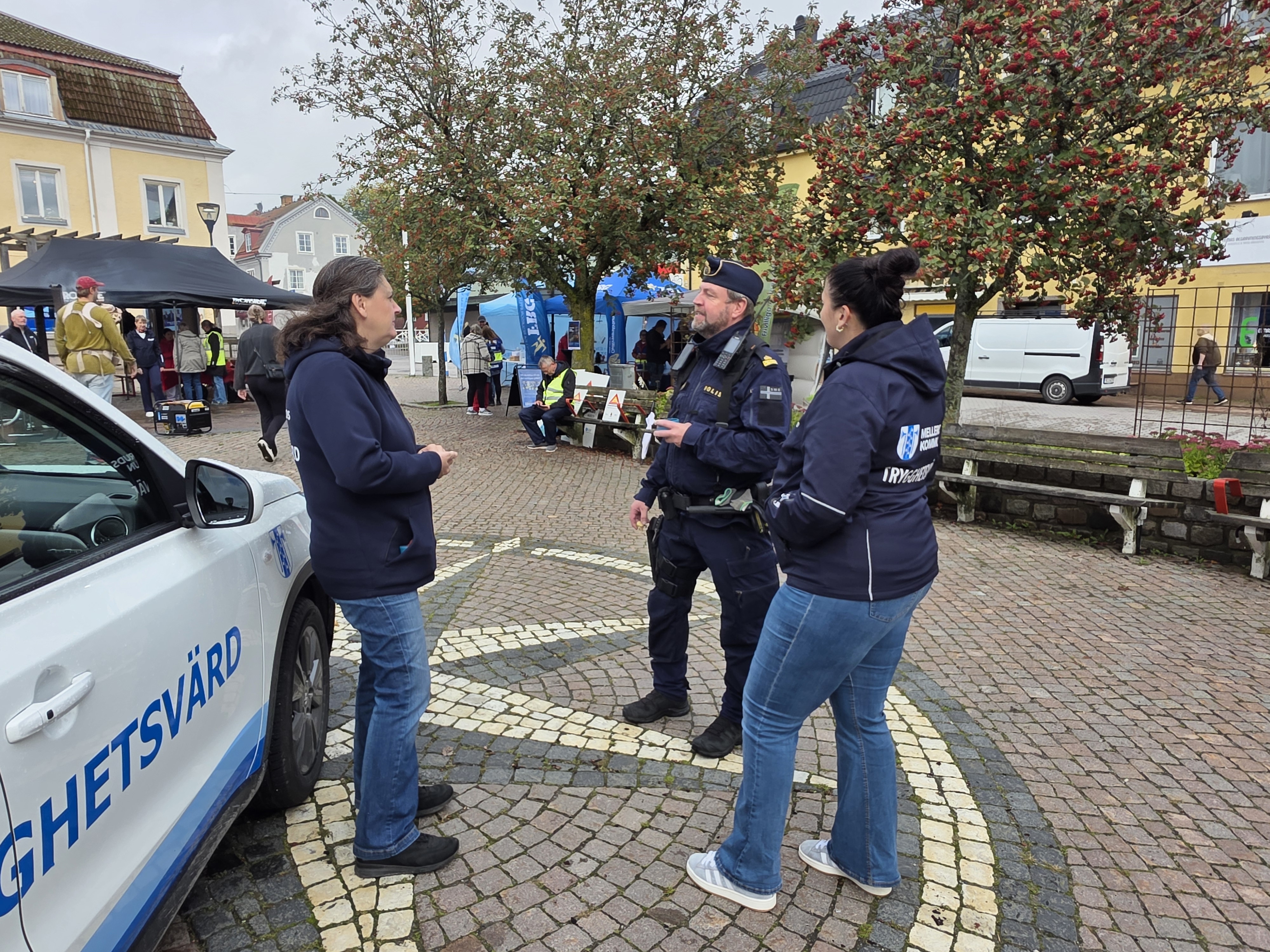 Polisen står och pratar med två trygghetsvärdar på torget i Mellerud
