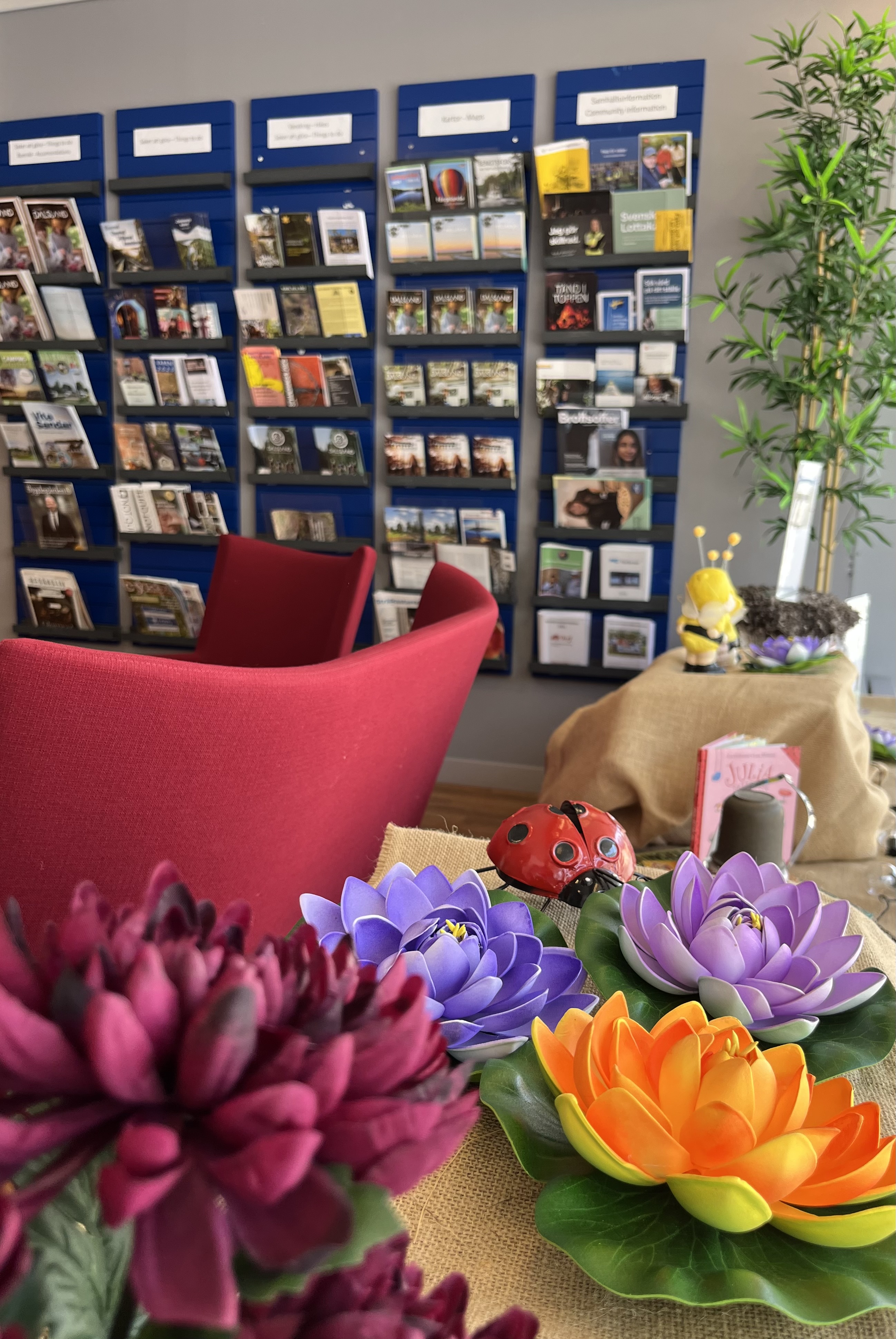 interiör Medborgarkontoret, broschyrväggen och blommor i förgrunden