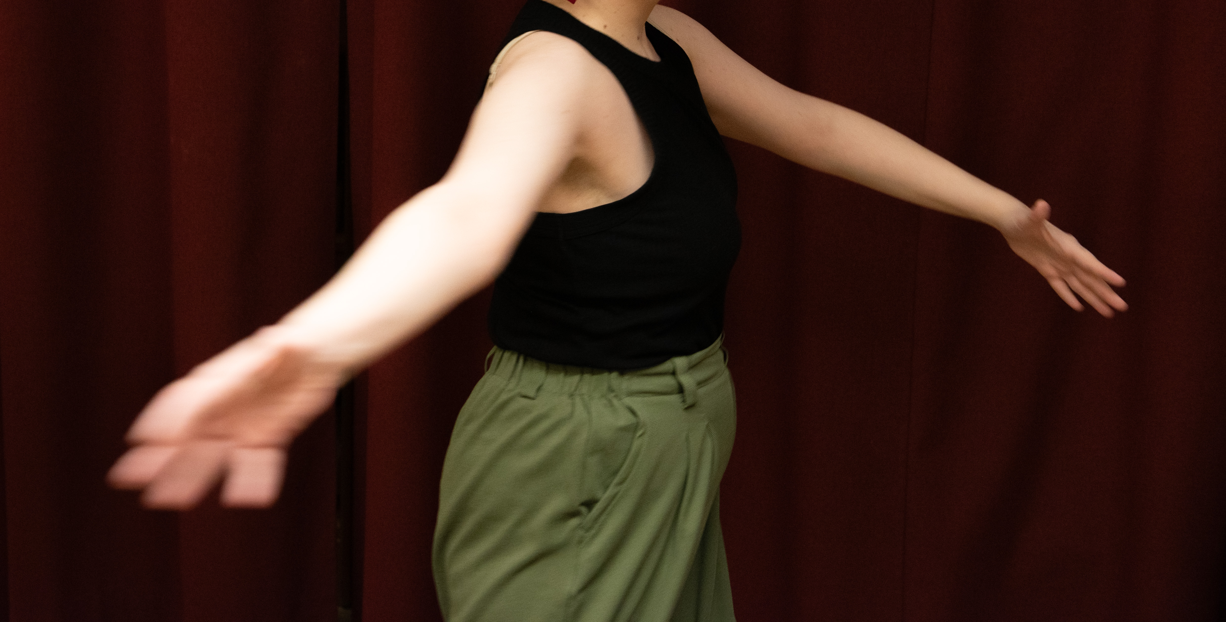 Bild på en dansande kvinna i gröna byxor och svart linne
