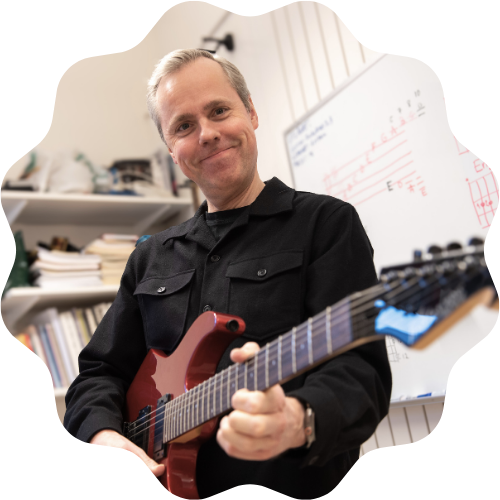 Foto på Dan som håller i en vinröd elgitarr