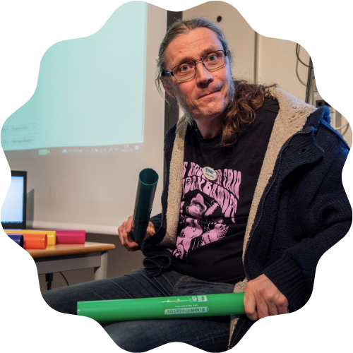 Foto på Andreas hållandes i färgglada rör som han kan spela melodier med genom att slå i knät.
