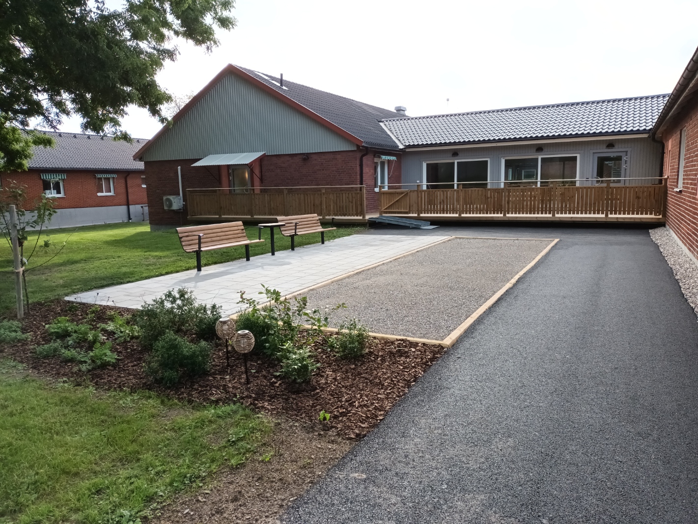 Boulbana med bänkar och en träramp i bakgrunden som går upp till altanen