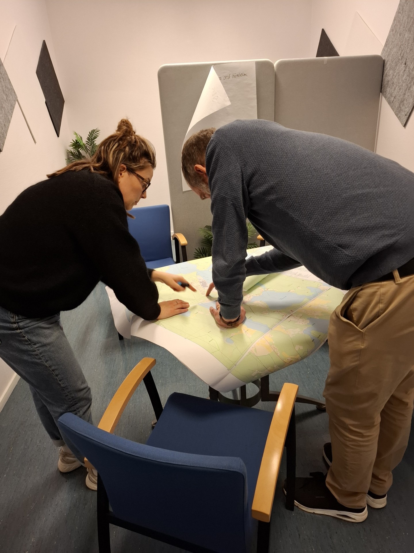 Två personer som står framåtböjda och kollar på en karta som ligger på ett bord