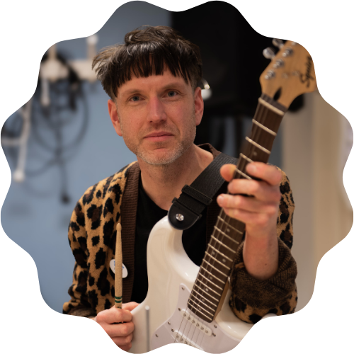 Foto på Daniel Olsson hållandes i en vit elgitarr.