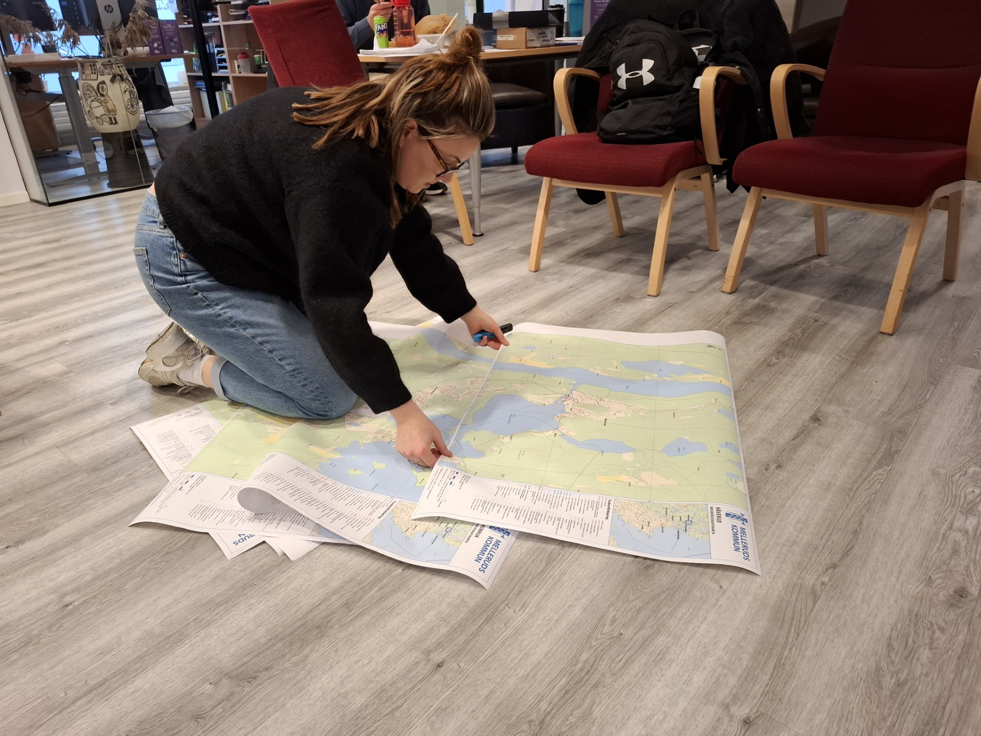 Person sitter på golvet med stora kartor framför sig och kollar på dessa